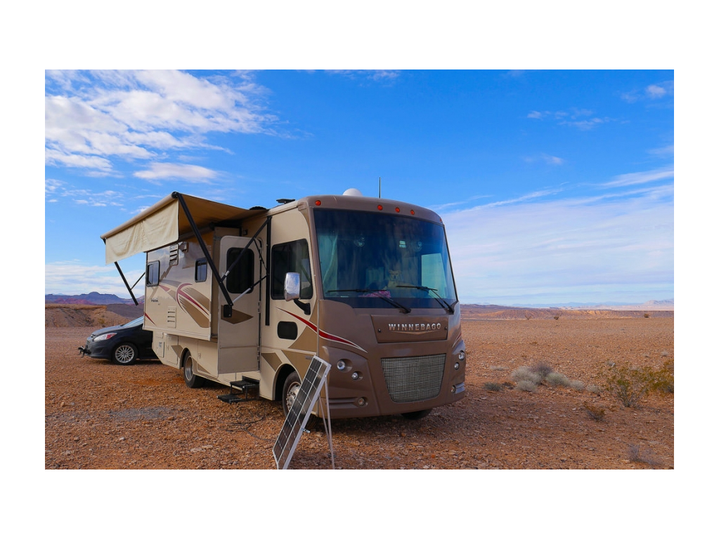 Winnebago Vista parked in desert landscape with portable solar panels in use