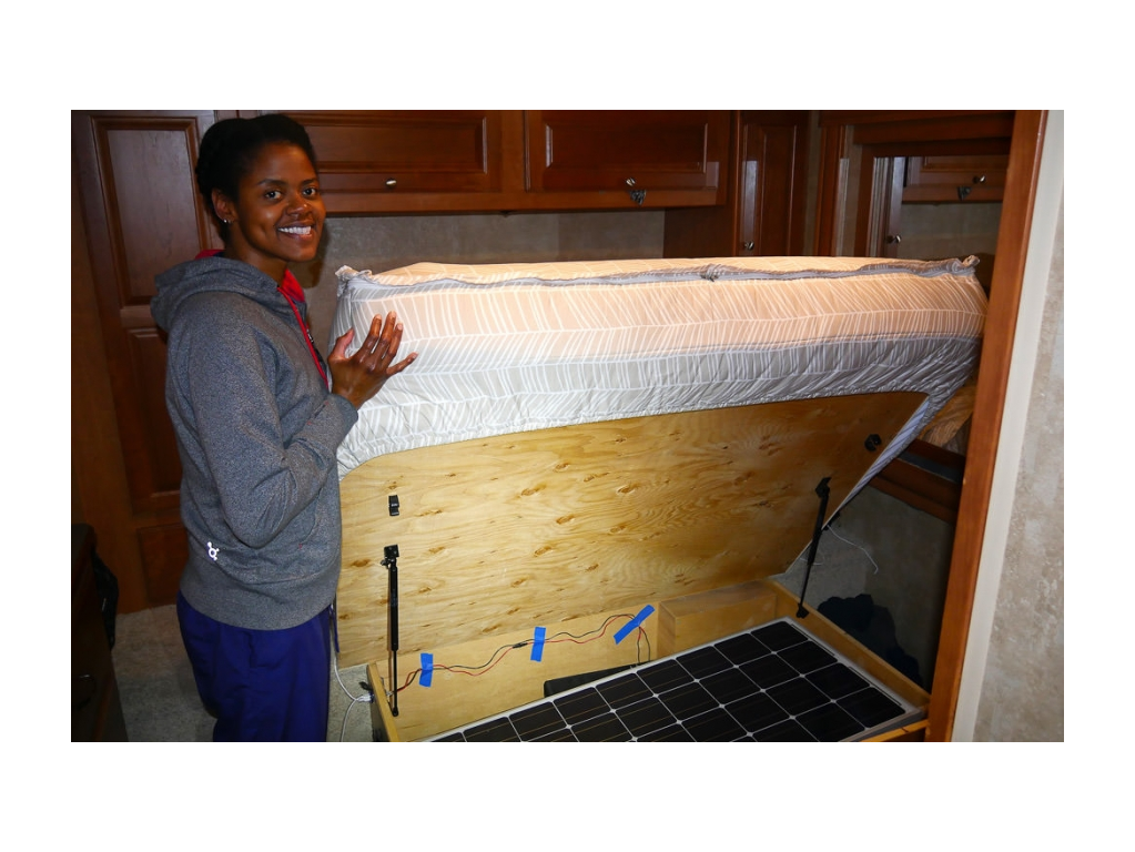 A young woman displaying the storage area used for storing portable solar panels