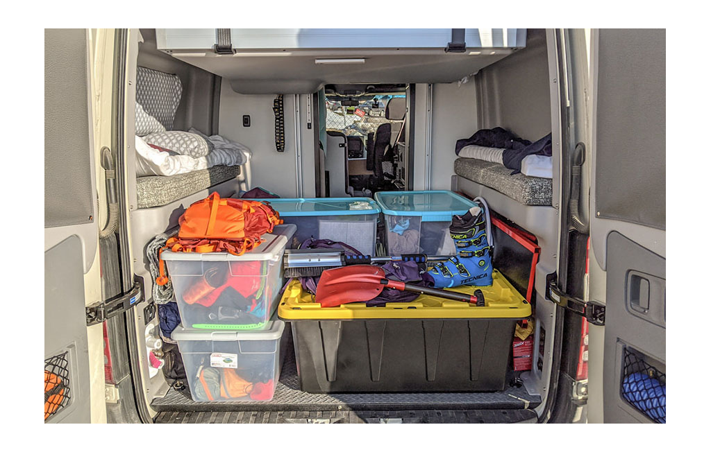 Storage bins with ski boots and other snow gear in the back of the Winnebago Revel.
