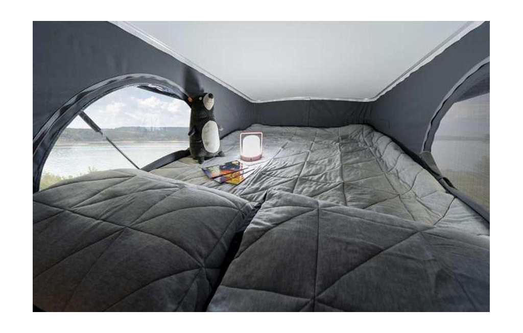 View of the Winnebago Solis pop-top bed with a lantern and stuffed animal on it.