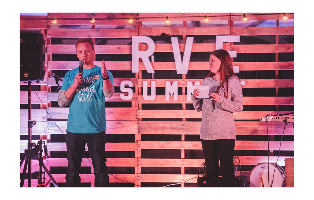 Alyssa and Heath standing on stage introducing speakers at the RVE Summit