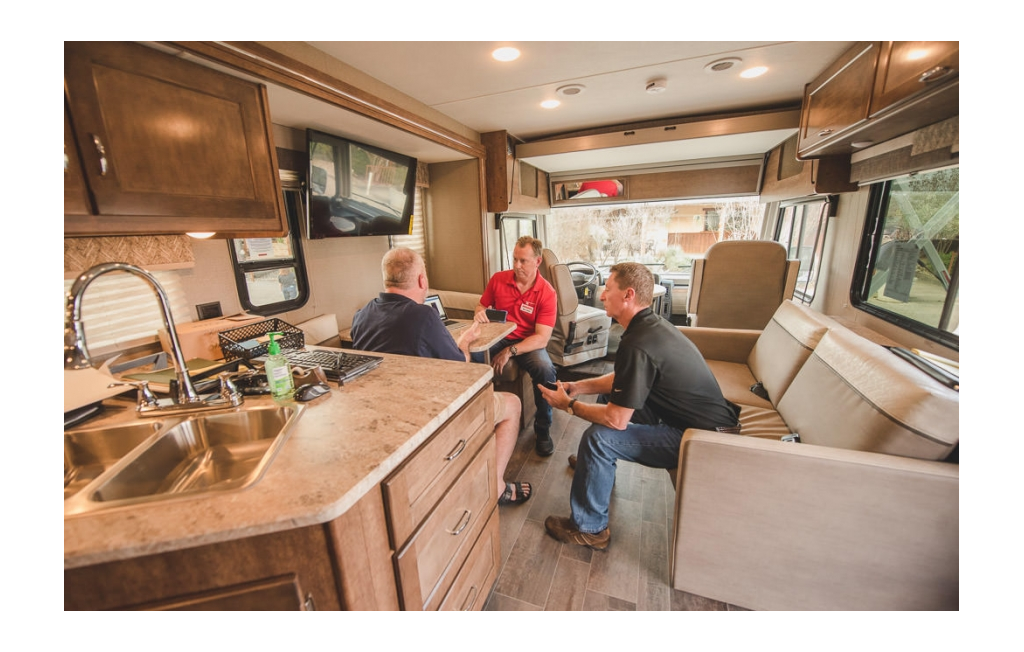 Two people from Winnebago talking with a Summit attendee inside the 'Winnebago Lab'