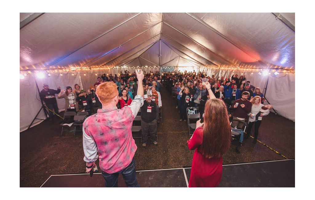Heath and Alyssa standing on stage toasting to a large crowd of people