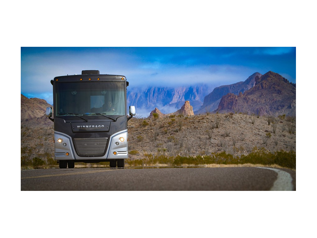 Adventurer driving down road with mountains and blue sky in background