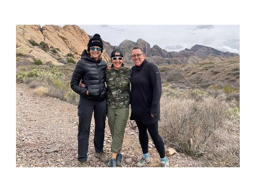 Three friends smiling for photo in front of mountains