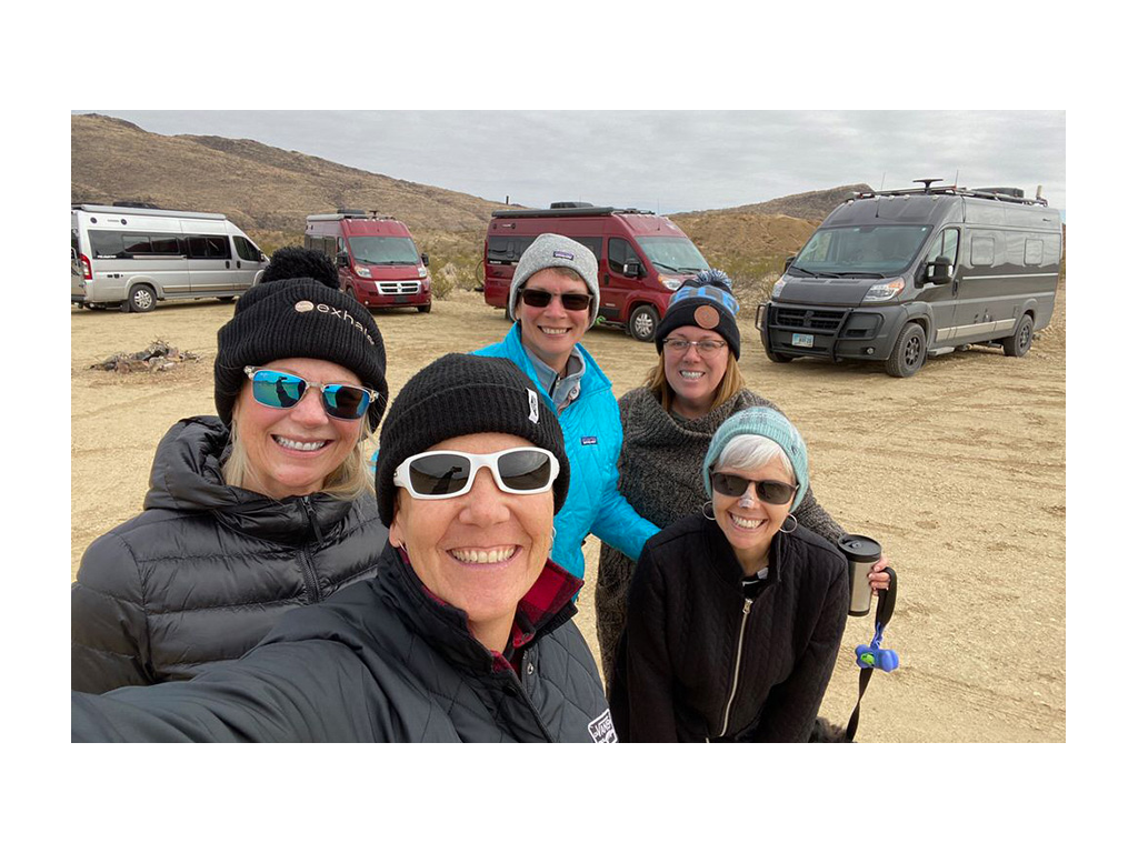 Travato friends huddled together for a picture with Travatos in background