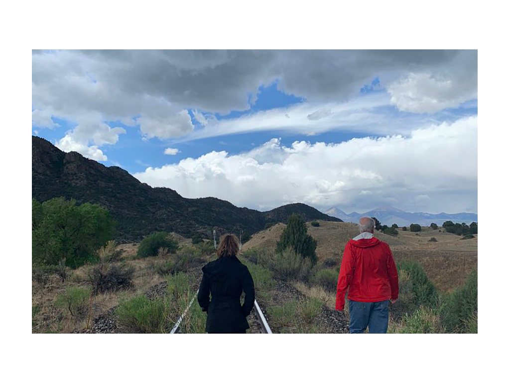 Alyssa and another person walking down the road towards mountains