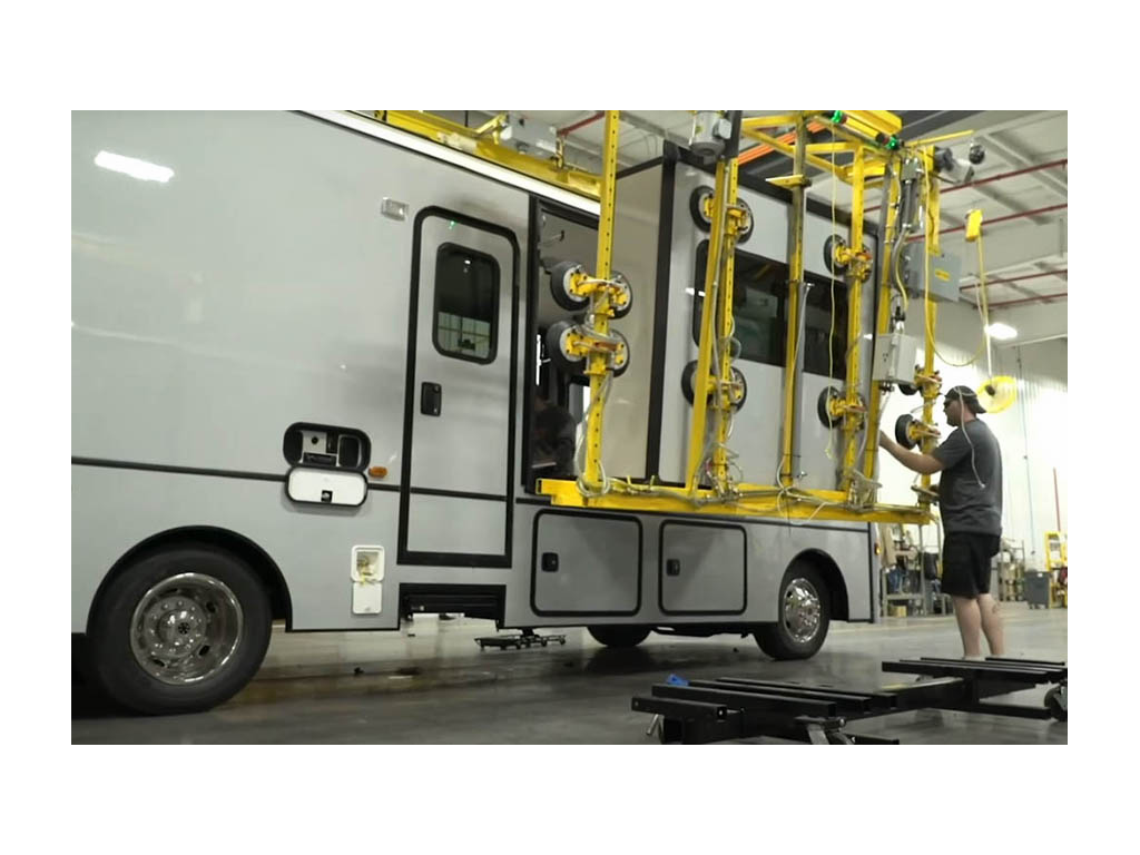 Inside Winnebago factory an employee is attaching a slide to a Class A motorhome