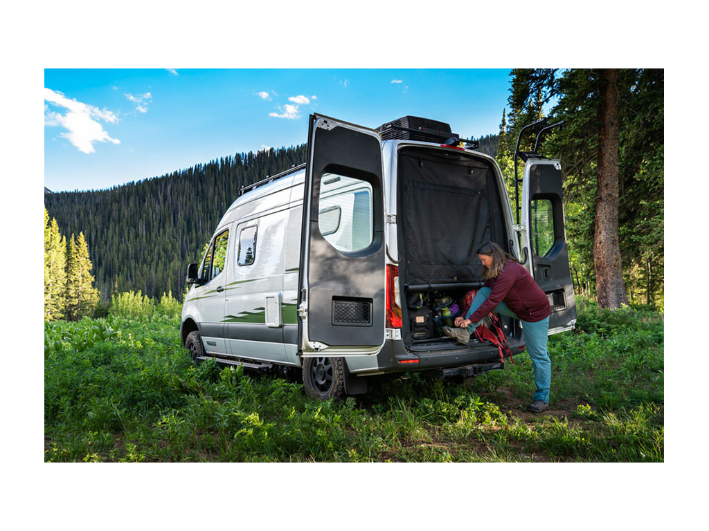 Kathy tying shoe on back of Revel with rear doors open