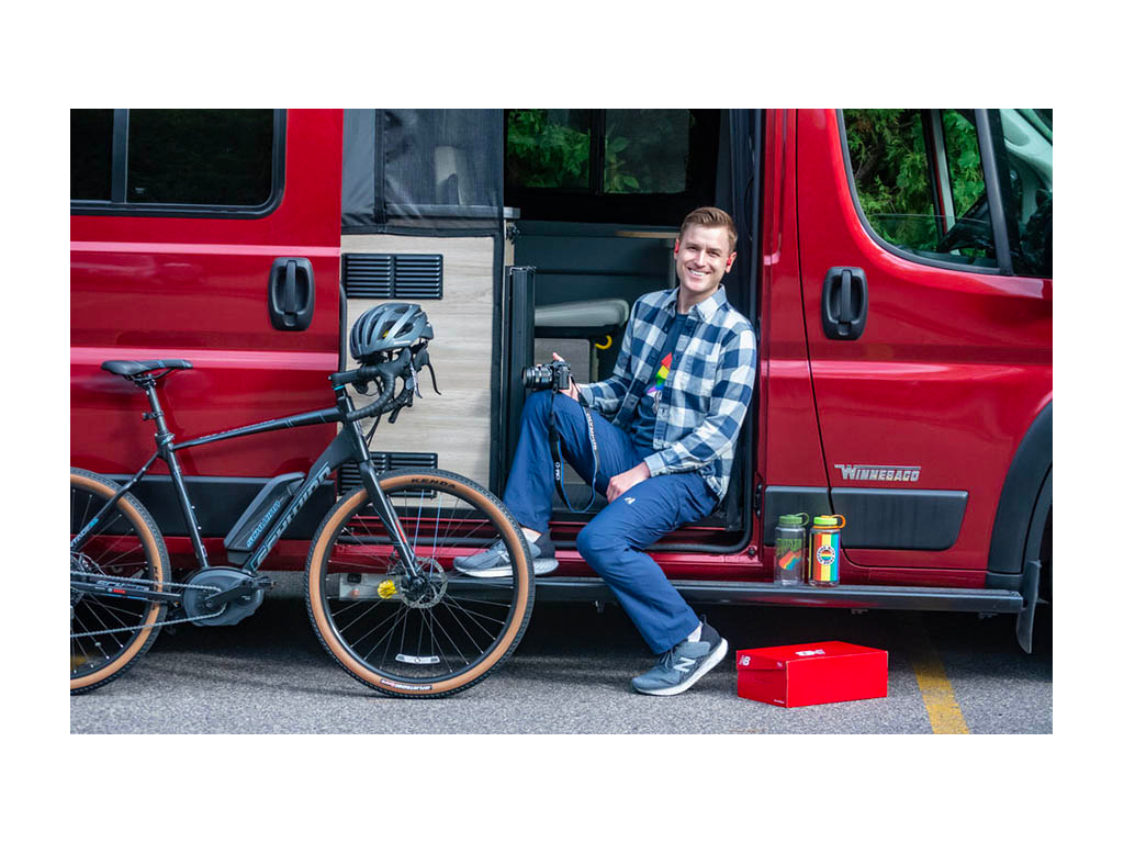 Mikah sitting in entry of Solis holding camera with bike nearby