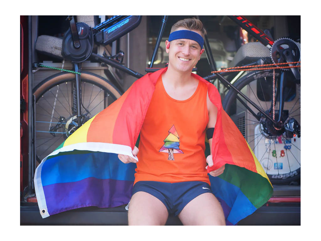 Mikah sitting on back of Solis full of bikes. Mikah has pride flag draped over shoulders