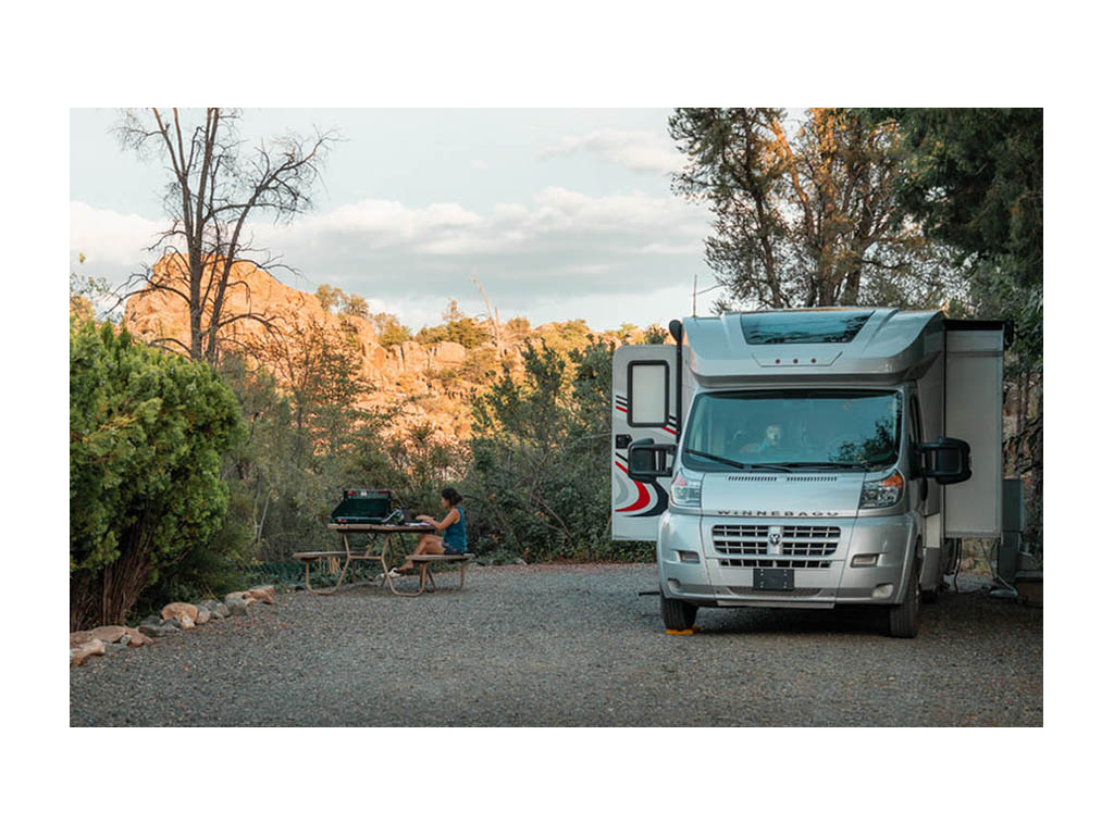 Trend parked at campsite. Nadia is sitting at picnic table working on laptop
