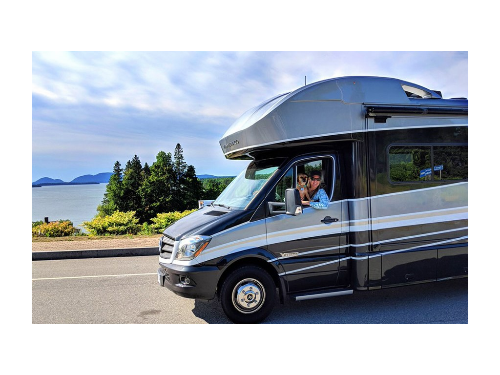 Katelyn Newstate driving Navion with dog on lap smiling out window