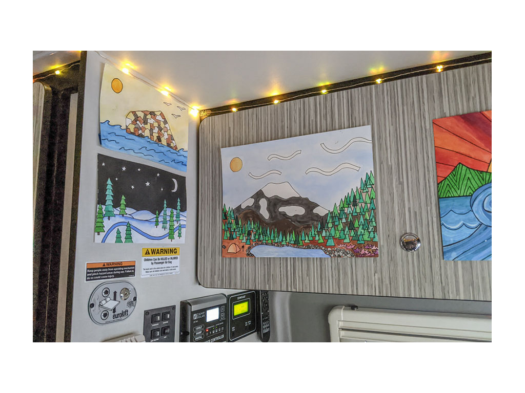 Interior of Gnar Wagon with painted pictures and string lights hanging above cabinets