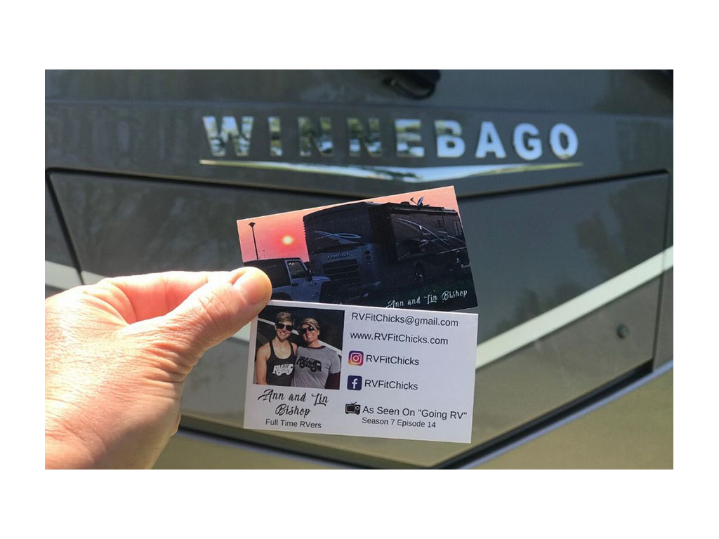 Card with contact information  held up in front of Winnebago Forza