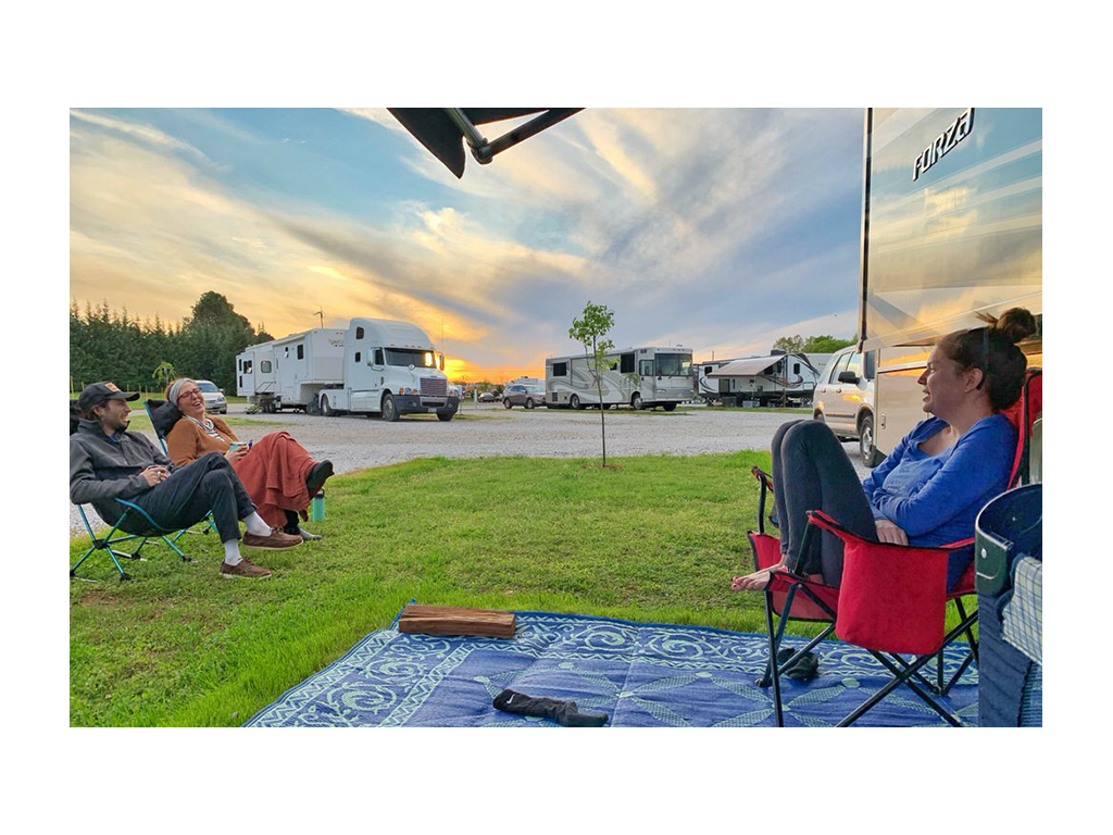 Alyssa sitting in a chair in front of Forza with two friends sitting in chairs at a distance