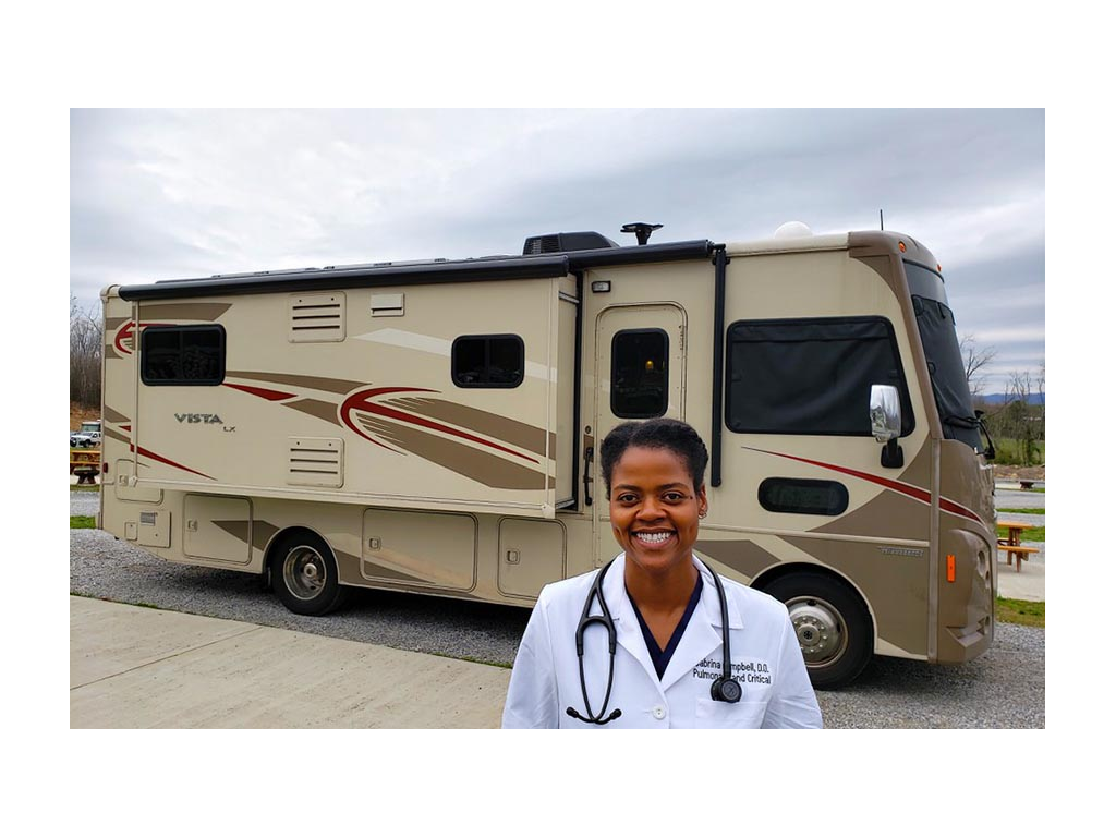 Sabrina standing in white doctor coat in front of Winnebago Vista