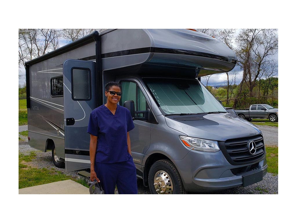 Sabrina wearing blue scrubs standing in front of Winnebago Vita