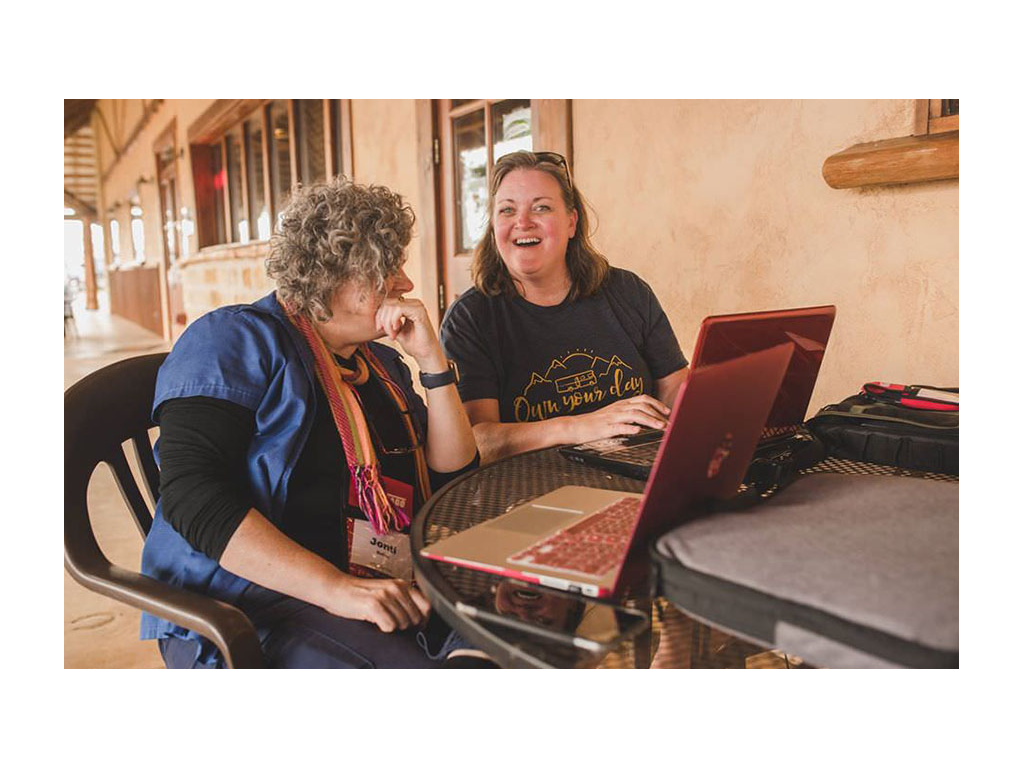 Two RVE attendees sitting at table with laptops in coworking space