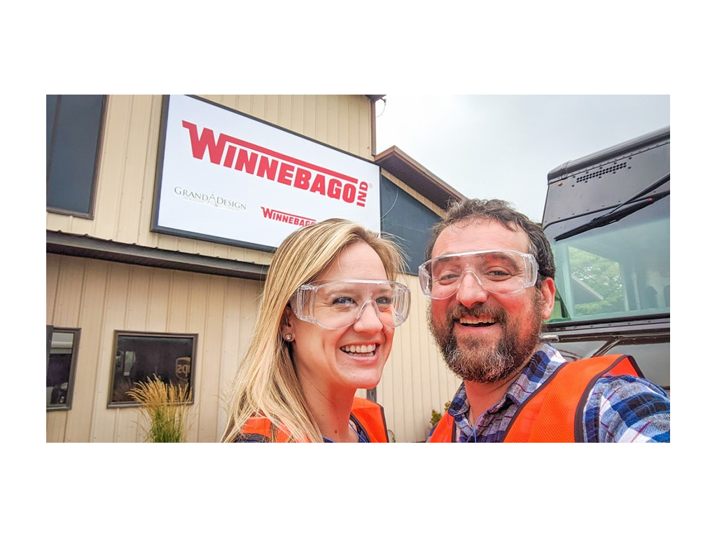 Katelyn and Howard Newstate wearing safety vests and glasses standing outside Winnebago Visitor Center for the Factory Tour
