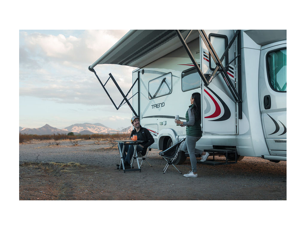 Nadia standing on step of Trend with door open looking at Jon sitting at table outside of Trend.