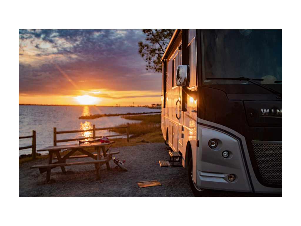 Adventurer parked near water at sunset