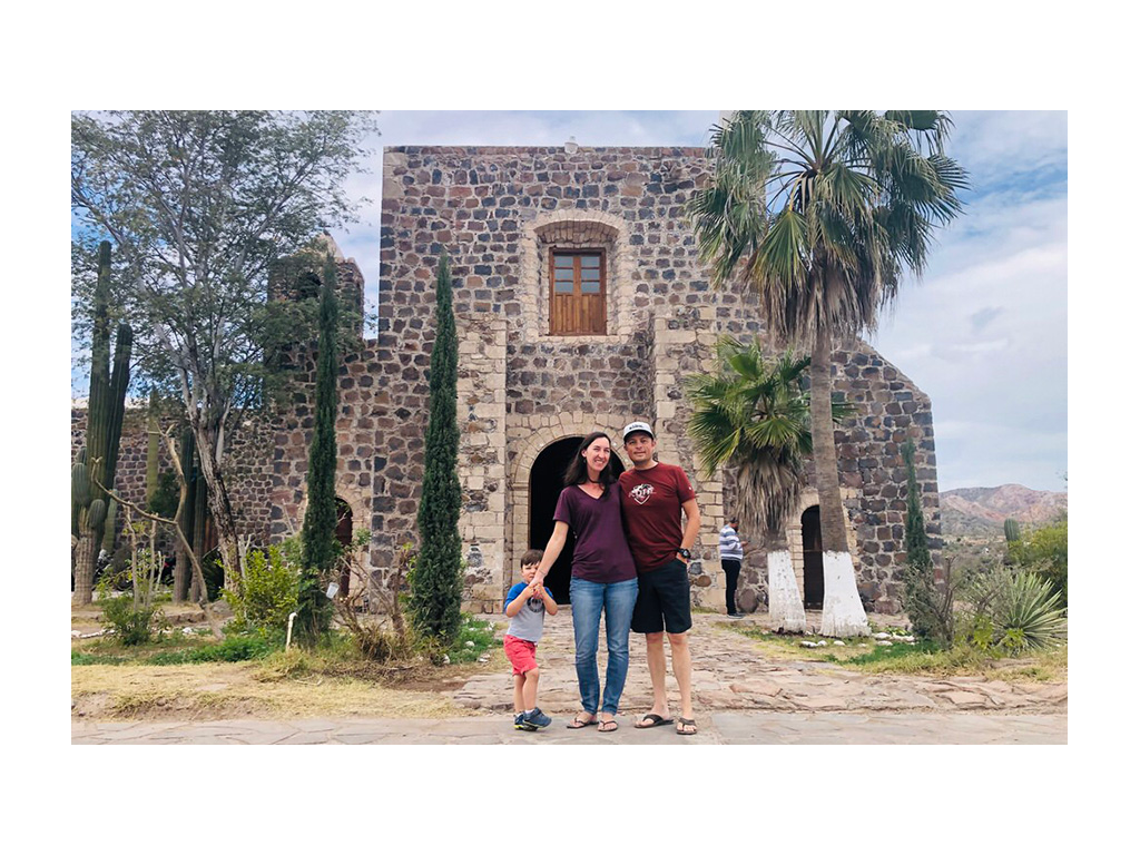 Highland family standing in front of large brick building in Baja