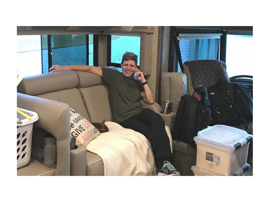 Ann sitting on couch with two plastic containers full of paperwork in front of her