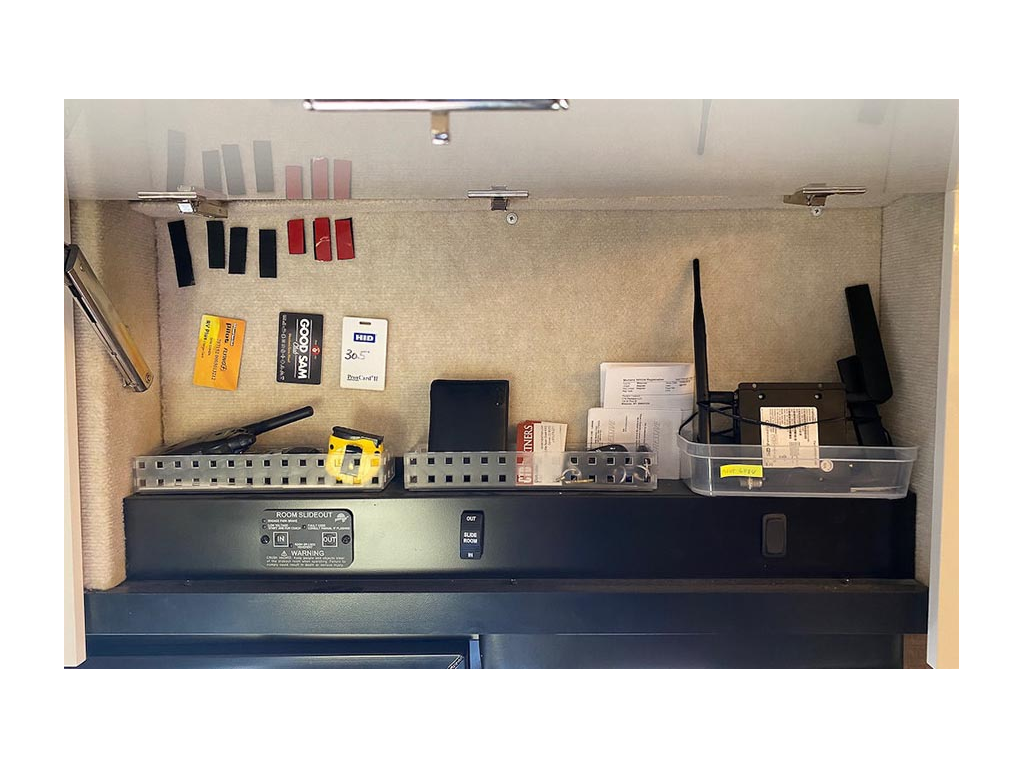 Cabinet full of miscellaneous items stuck to tan carpeted wall with Velcro