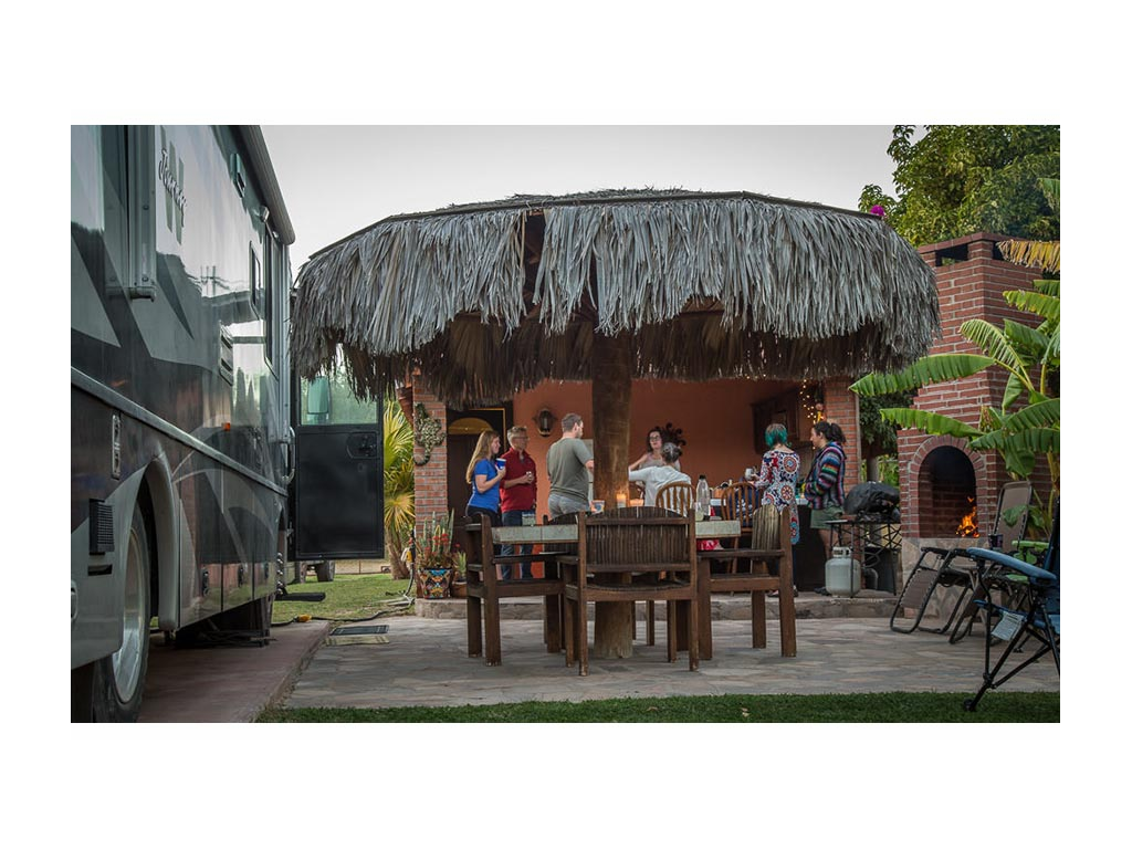 Seven people talking on the patio next to the Journey