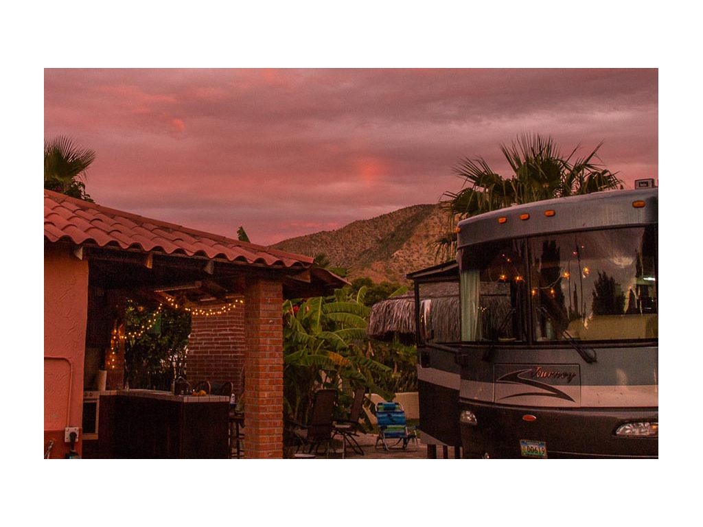 Pink sunset above mountaintop with a view of Journey parked next to the house
