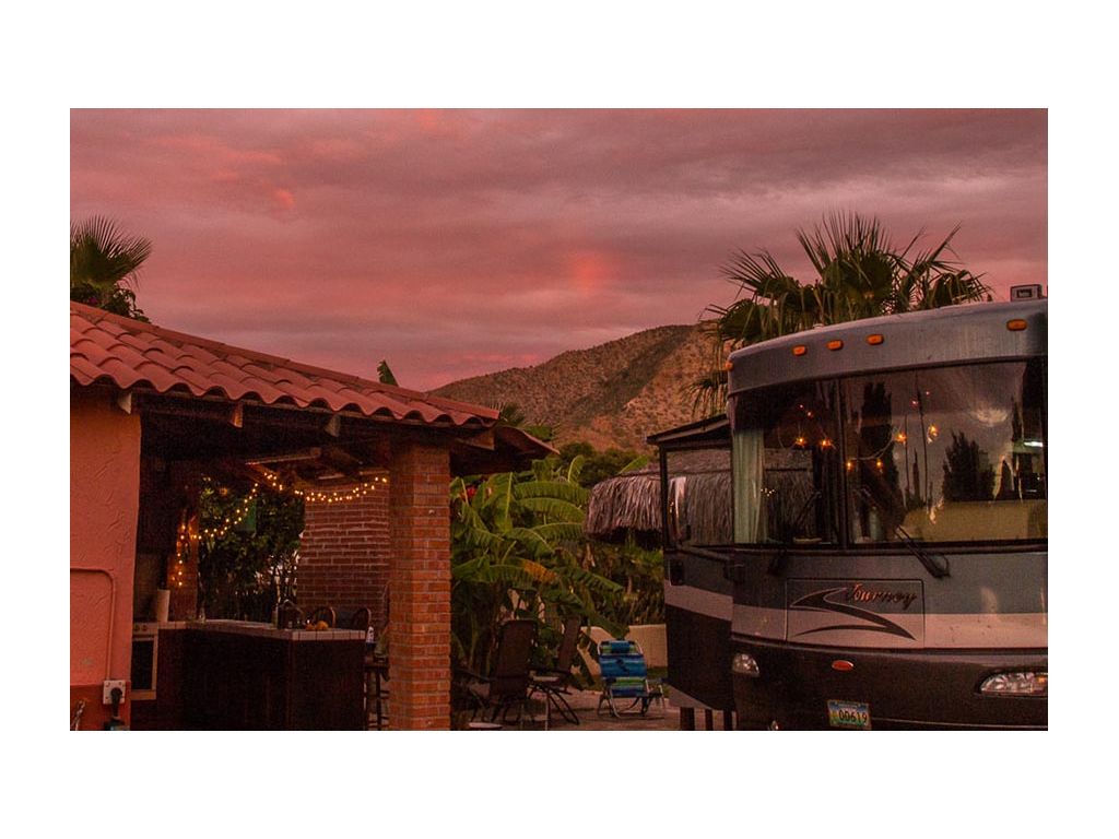 Pink sunset above mountaintop with a view of Journey parked next to the house 