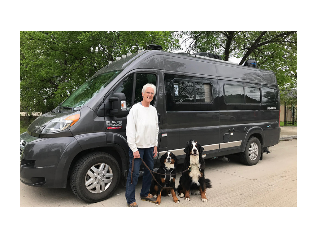 Beth in front of Travato with two Bernese Mountain Dogs on leash