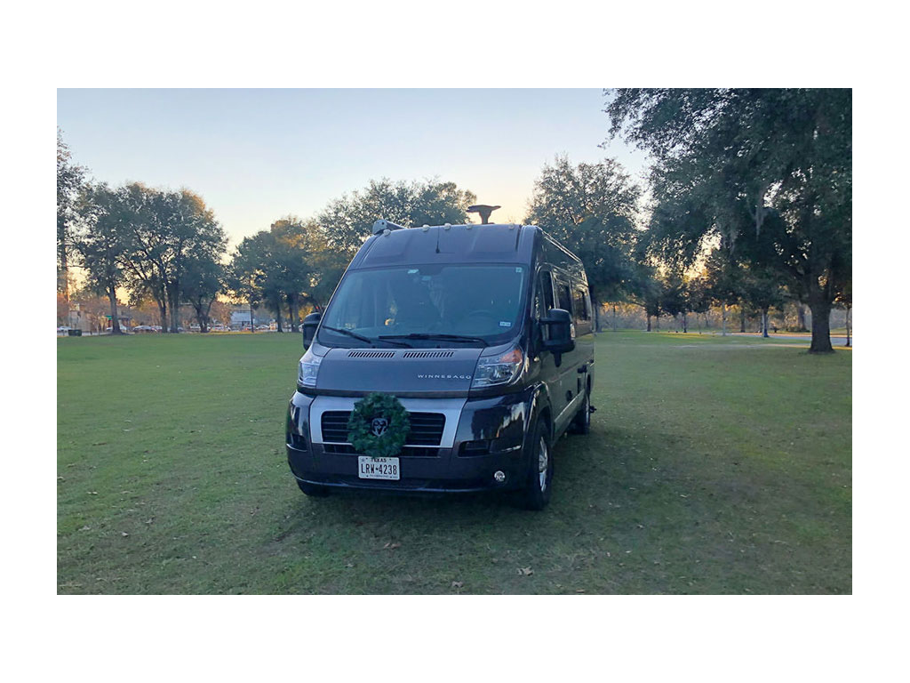 Travato parked on grass with a green wreath on front grill
