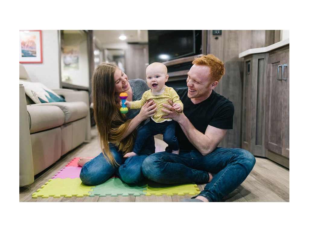 Alyssa and Heath holding up Ellie in the living room of their Forza