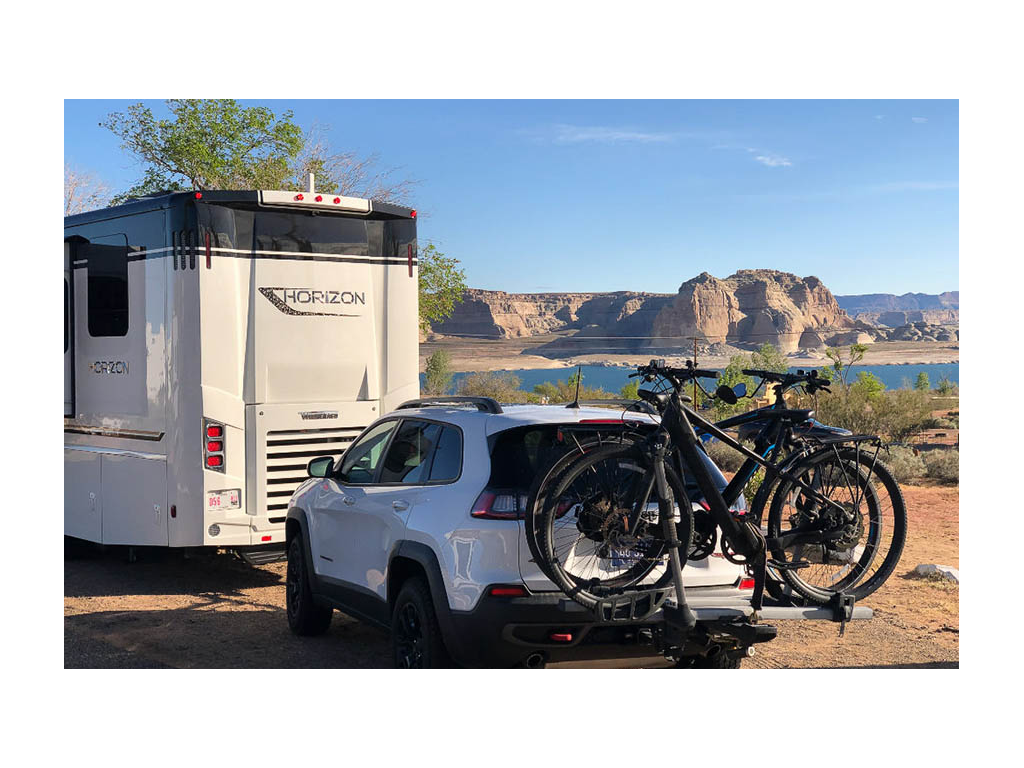 Winnebago Horizon with white tow car parked near blue water
