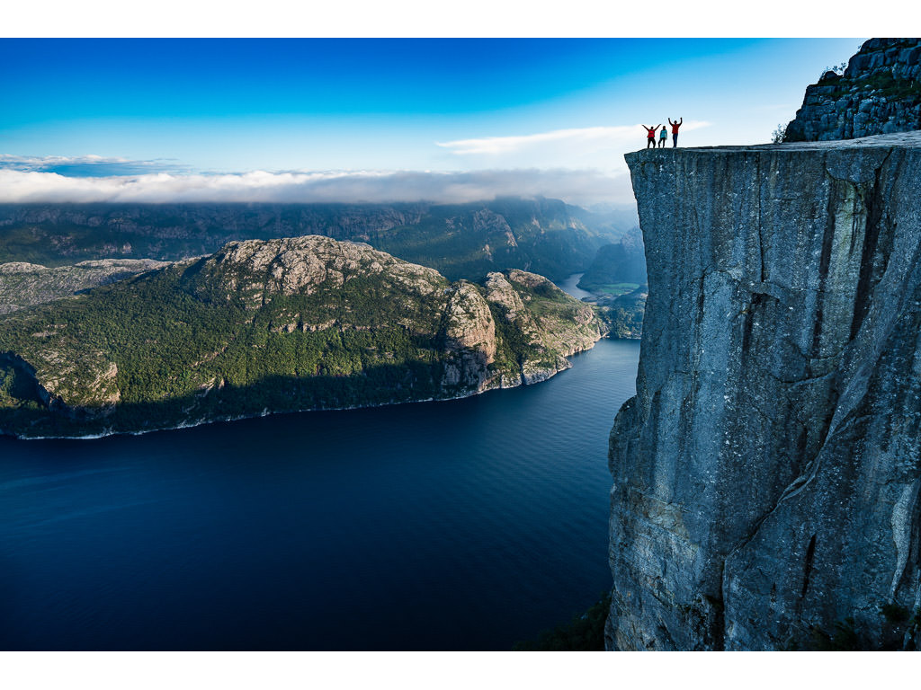 The Holcombes standing at the edge of Pulpit Rock looking over a landscape of water and mountains