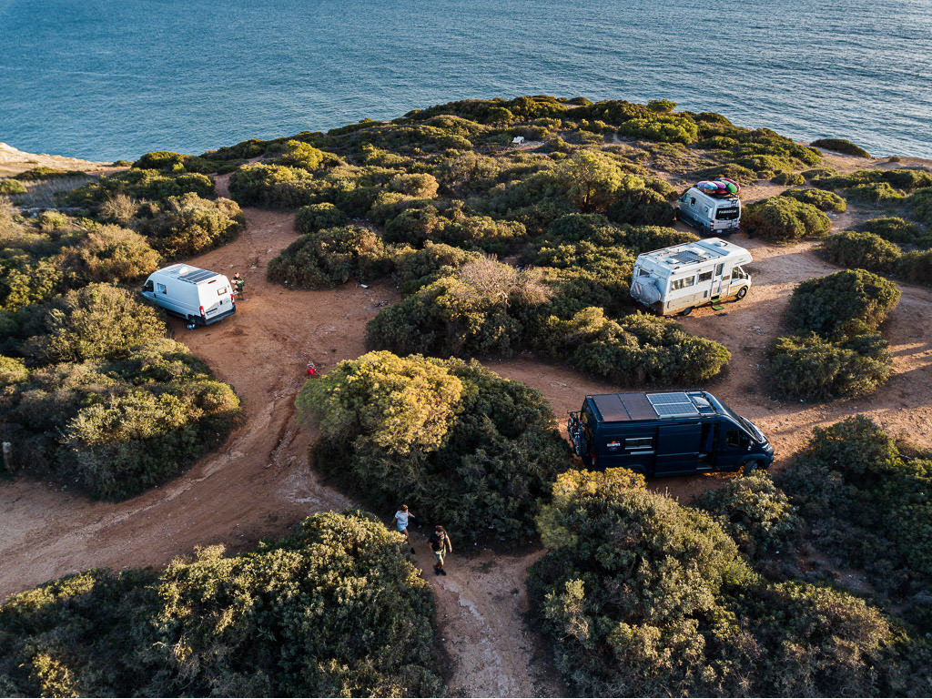 Winnebago Revel parked with 3 other motorhomes next to a body of water