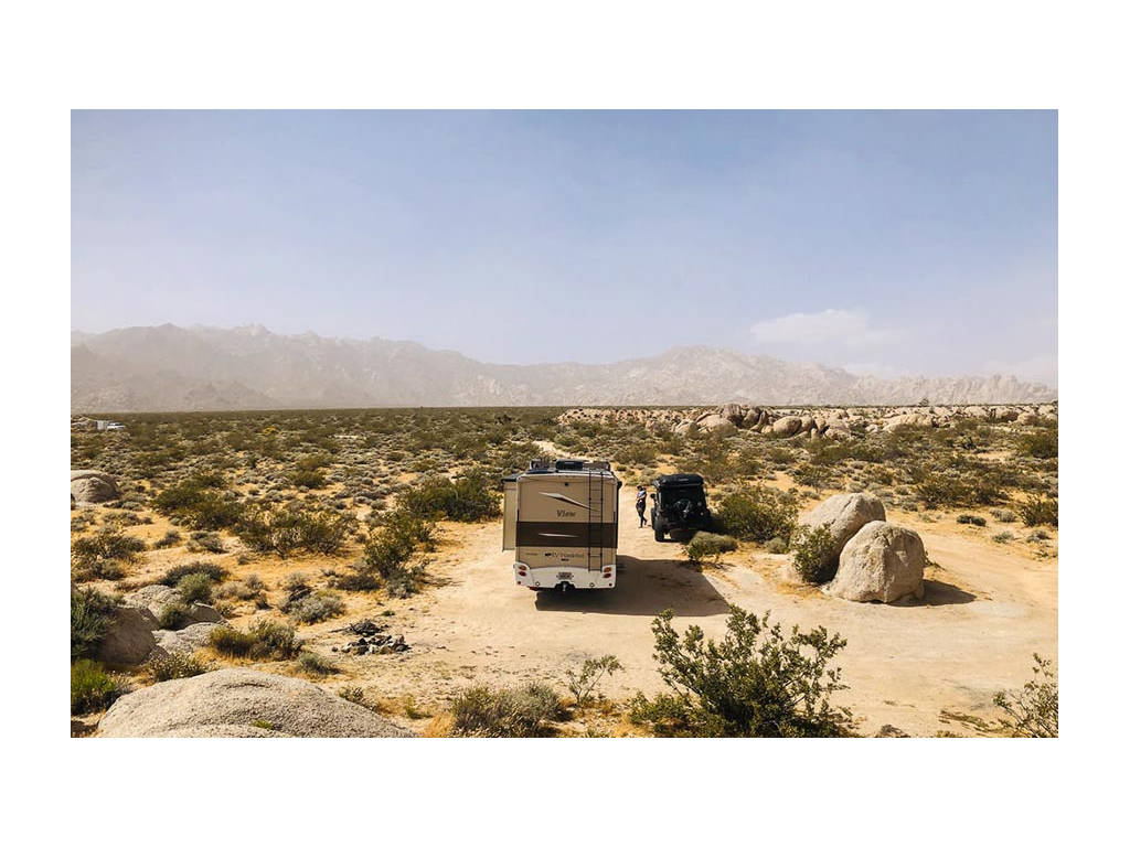 View and tow car parked in desert with mountains in the distance