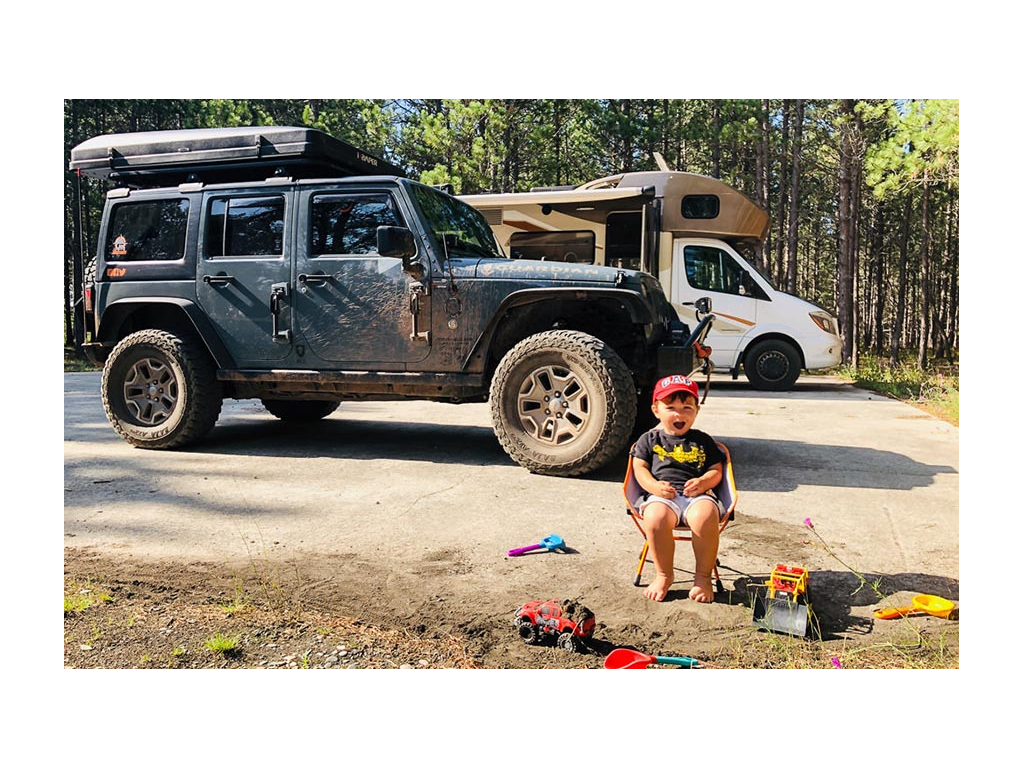Caspian sitting in a chair playing with toys. Tow car and View are in background