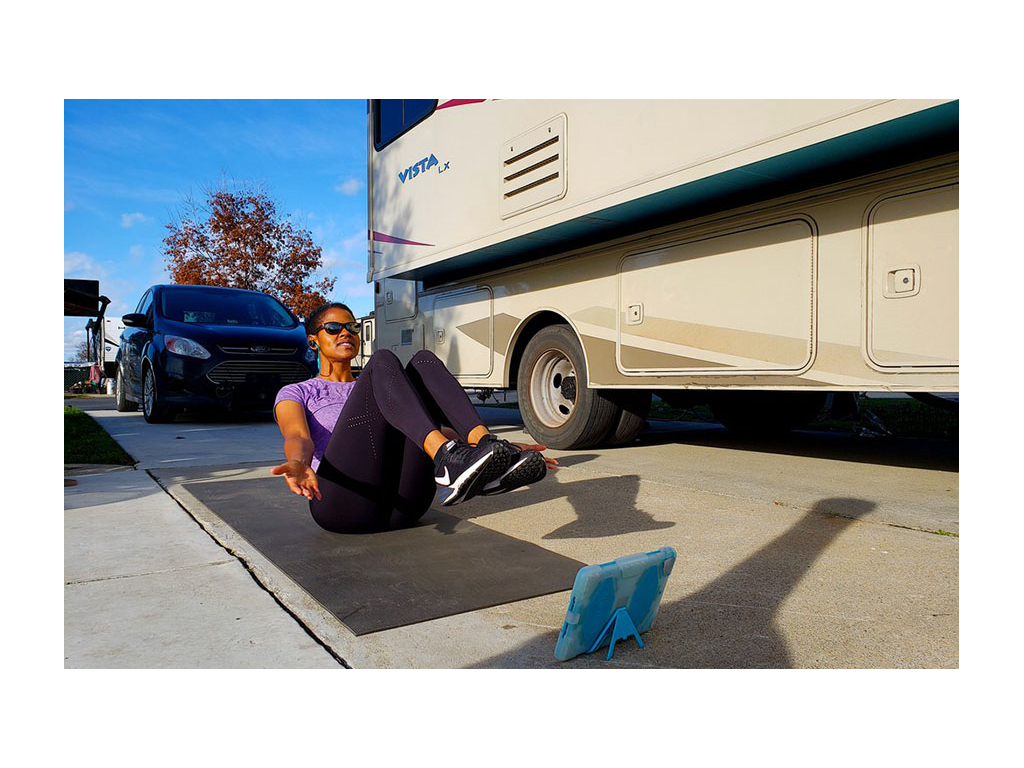 Sabina sitting next to Vista on a yoga mat using iPad for a workout