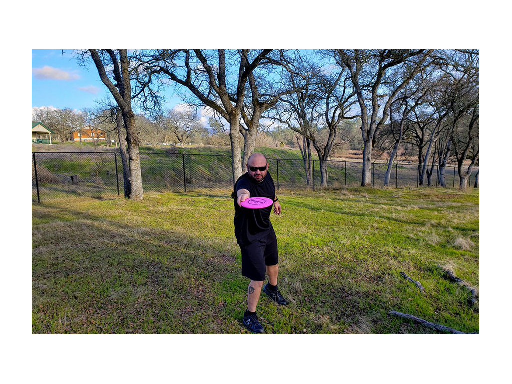 Kenny throwing pink Frisbee in grass