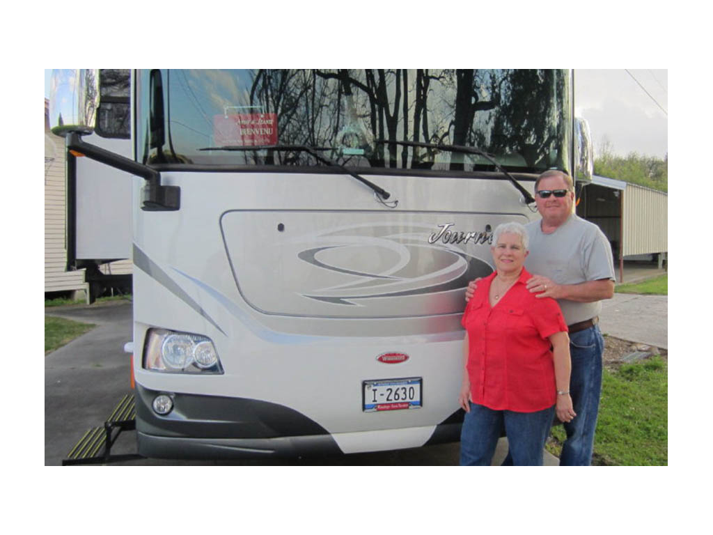 Jeanie and Andy smiling in front of Winnebago Journey.