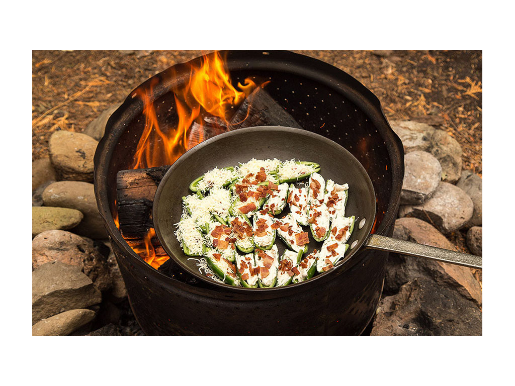 Jalapeno poppers in a pan roasting over a campfire 