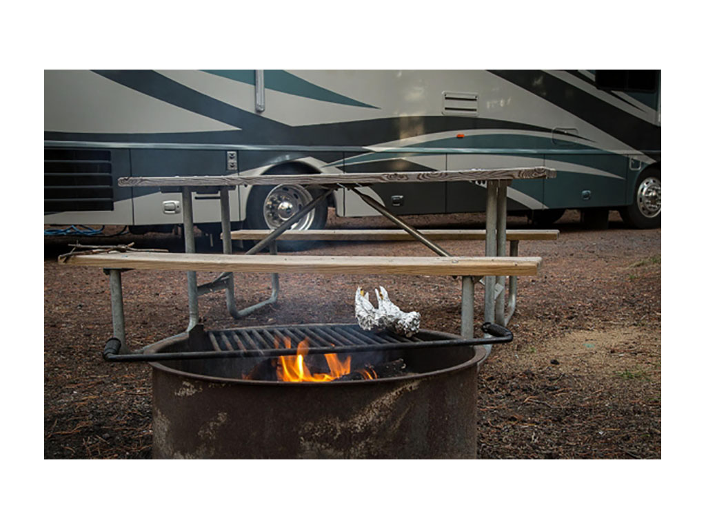 Campfire with picnic table and Winnebago Journey in background