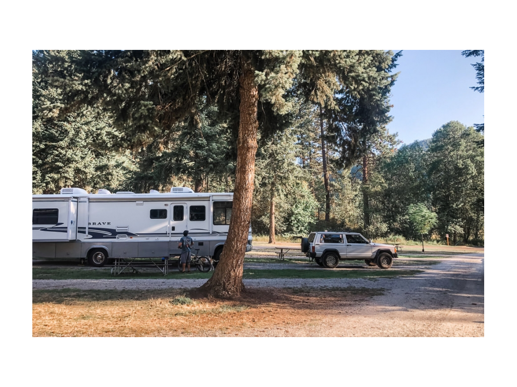 Winnebago Brave parked at campsite behind tow car and picnic table