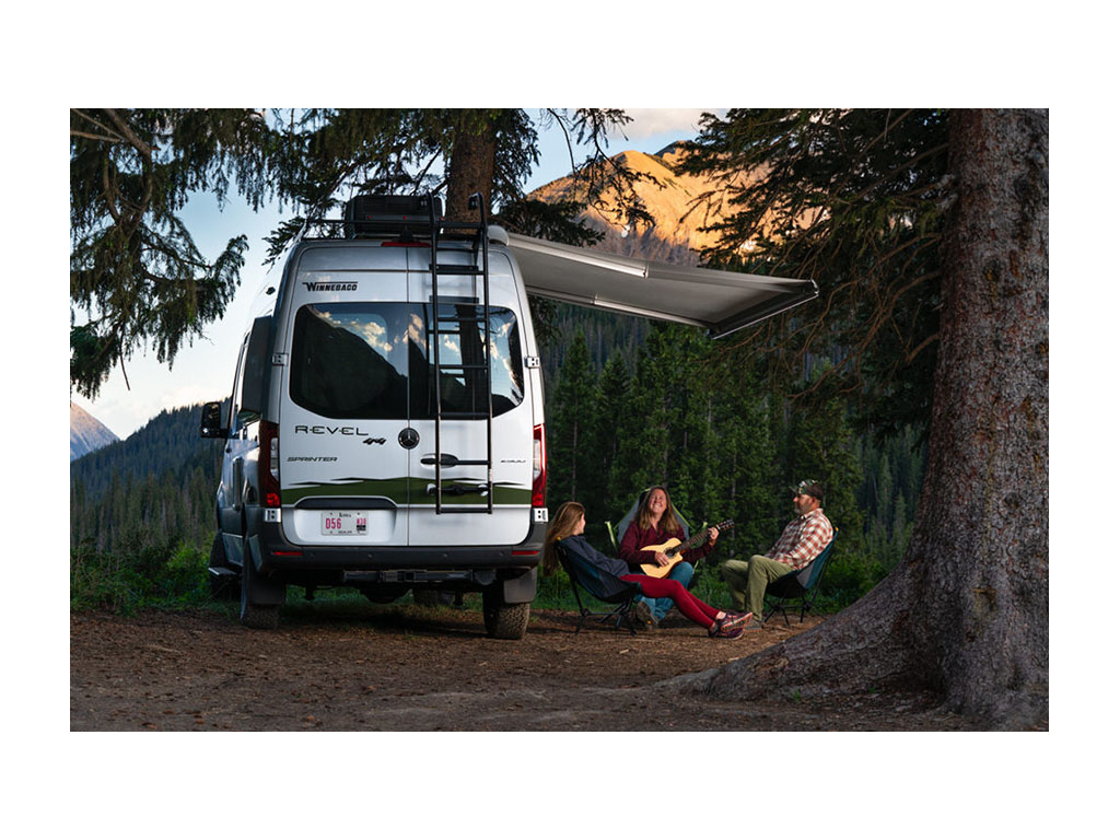 Abby, Kathy and Peter sitting outside under Revel awning. Kathy is playing guitar