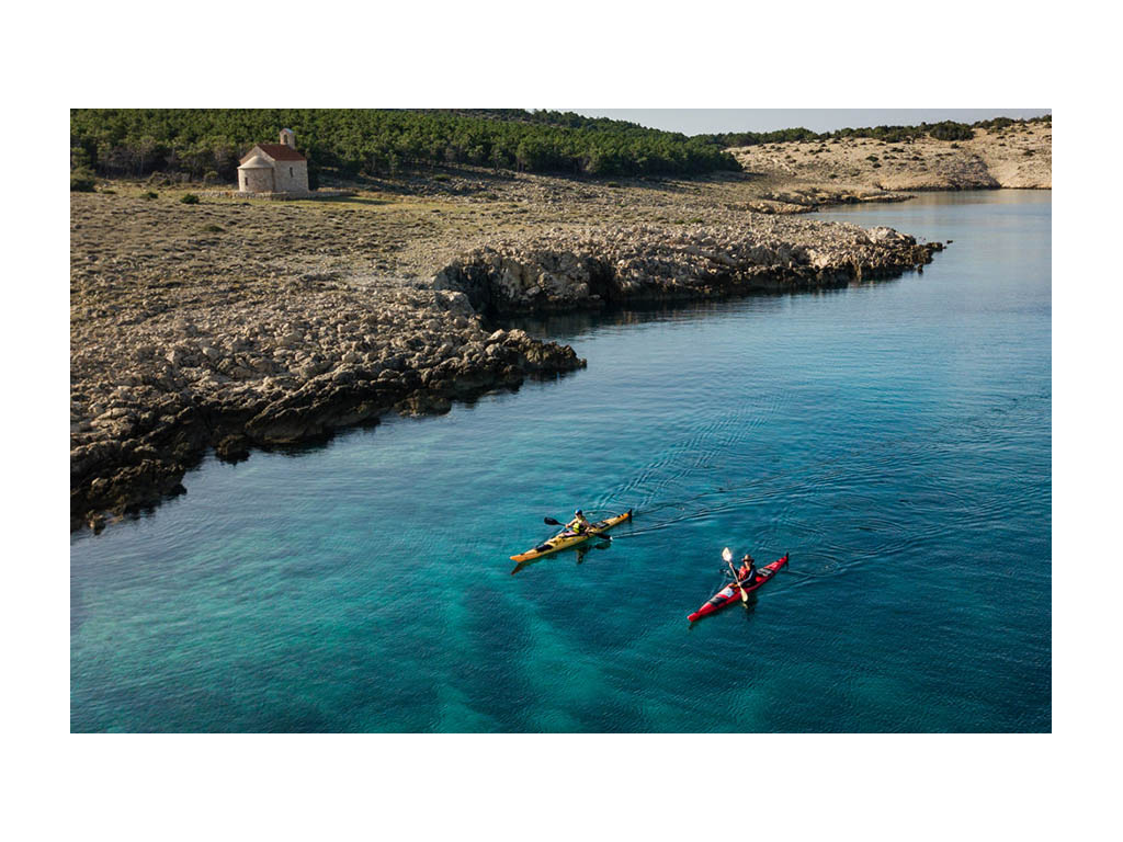 Border separating windward and leeward side of the Isle of Rab with Abby and Kathy on kayaks in water