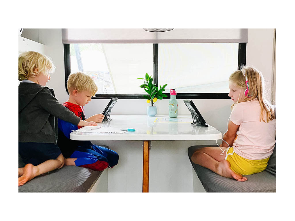 Three kids sitting at dinette playing on iPads