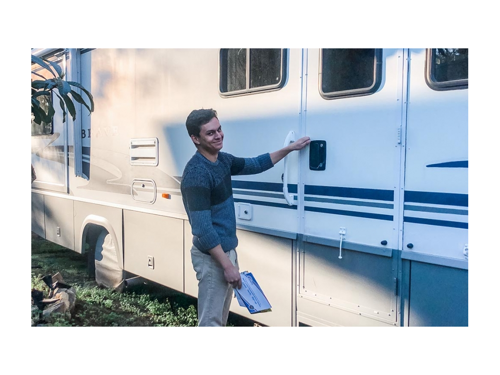 Jessie opening RV door while holding a stack of mail